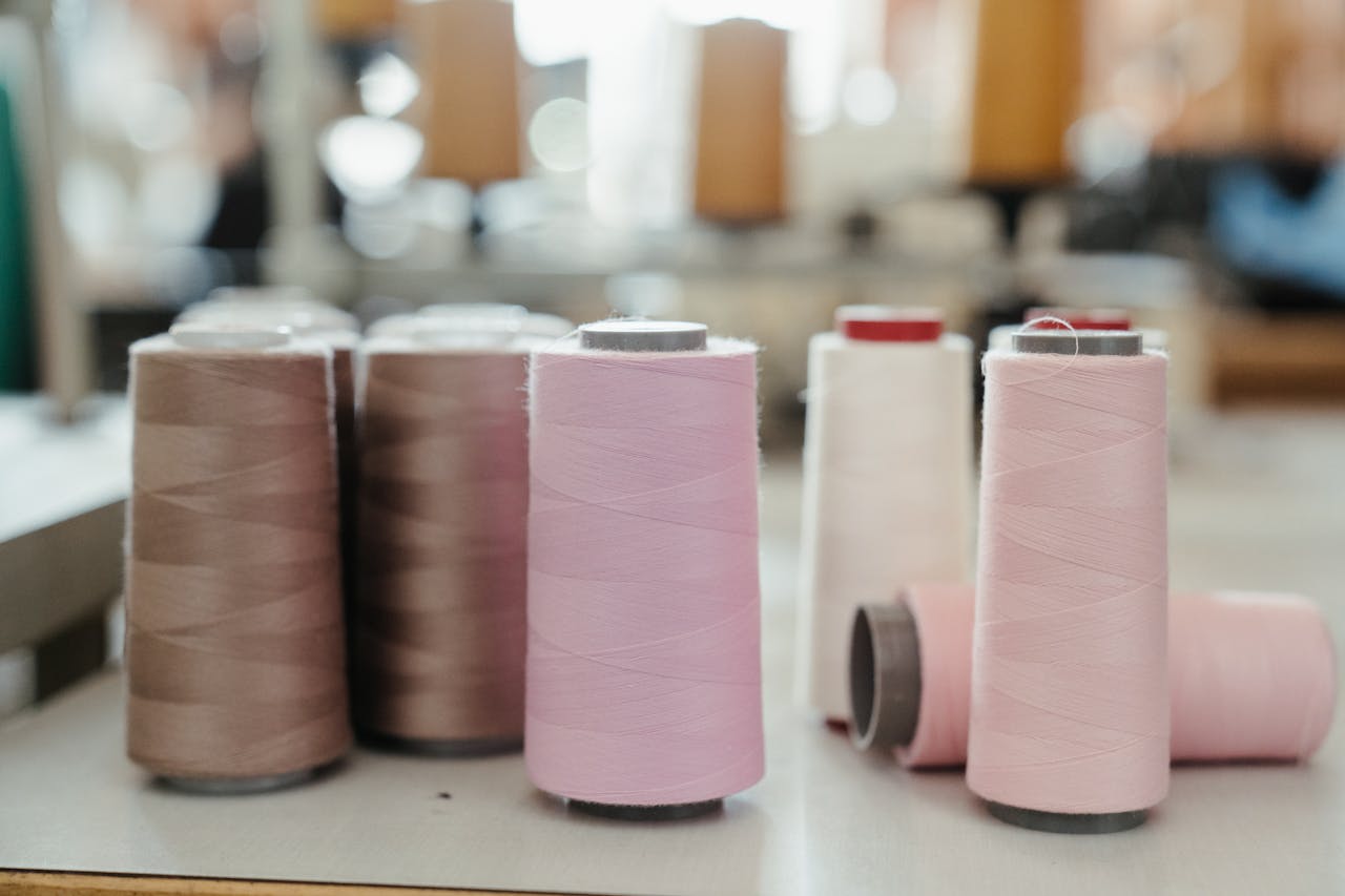 Close-up view of various colored thread spools in a sewing workshop setting.